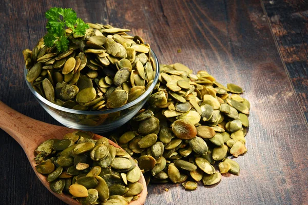 Composition with bowl of pumpkin seeds on wooden table — Stock Photo, Image