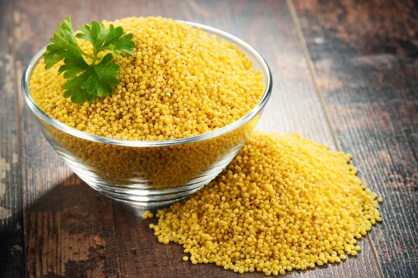 Composition with bowl of millet on wooden table — Stock Photo, Image