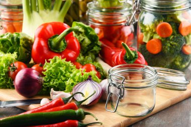 Kavanoz ile marine edilmiş yiyecek ve çiğ sebze kesme tahtası üzerinde