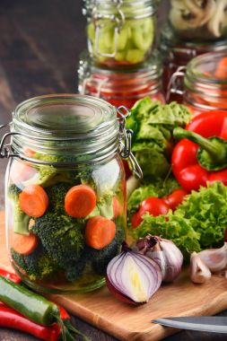 Kavanoz ile marine edilmiş yiyecek ve çiğ sebze kesme tahtası üzerinde