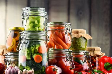 Jars with marinated food and organic raw vegetables clipart