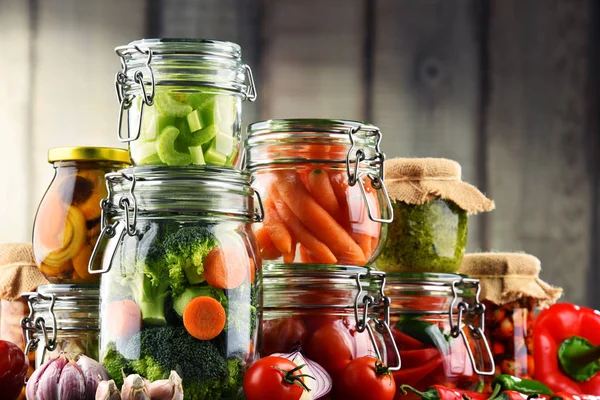 Jars with marinated food and organic raw vegetables — Stock Photo, Image