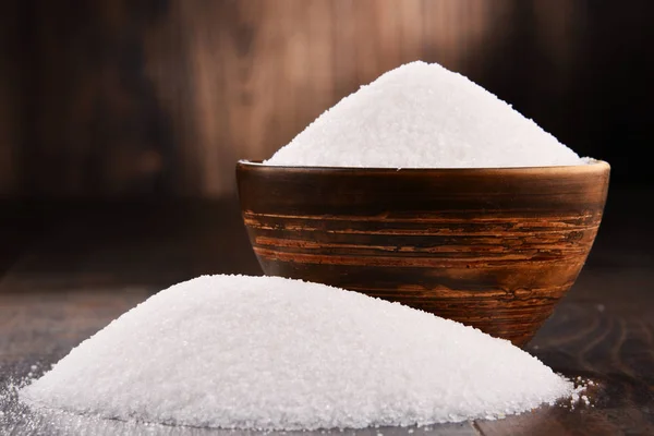 Состав с миской белого рафинированного сахара на деревянном столе — стоковое фото