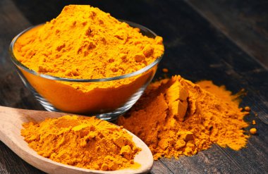 Ahşap masa üzerinde zerdeçal tozu kase ile kompozisyon