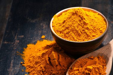 Ahşap masa üzerinde zerdeçal tozu kase ile kompozisyon