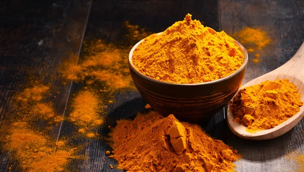 Composition with bowl of turmeric powder on wooden table — Stock Photo, Image