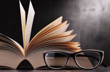 Açık kitap ve masanın üzerine gözlük ile kompozisyon