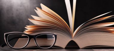 Açık kitap ve masanın üzerine gözlük ile kompozisyon
