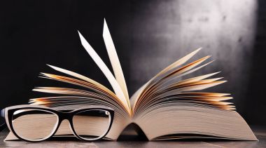 Açık kitap ve masanın üzerine gözlük ile kompozisyon