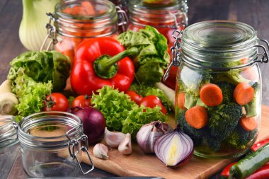 Kavanoz ile marine edilmiş yiyecek ve çiğ sebze kesme tahtası üzerinde