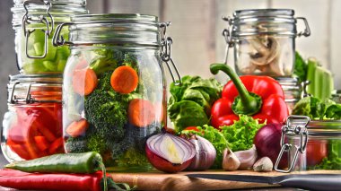 Kavanoz ile marine edilmiş yiyecek ve çiğ sebze kesme tahtası üzerinde