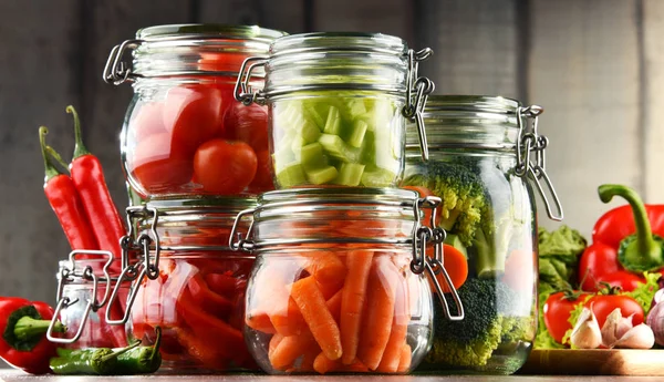 Jars with marinated food and organic raw vegetables — Stock Photo, Image