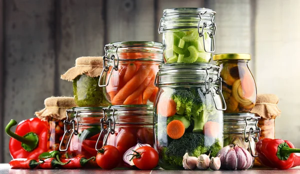 Банки с маринованной пищей и органическими сырыми овощами — стоковое фото
