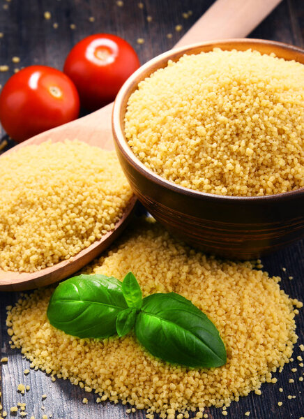 Bowl of uncooked couscous on wooden table