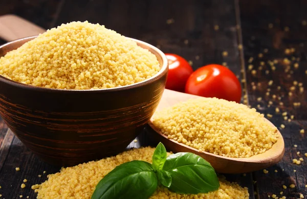 Bowl of uncooked couscous on wooden table — Stock Photo, Image