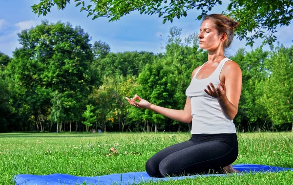 Jovem mulher durante meditação de ioga no parque — Fotografia de Stock