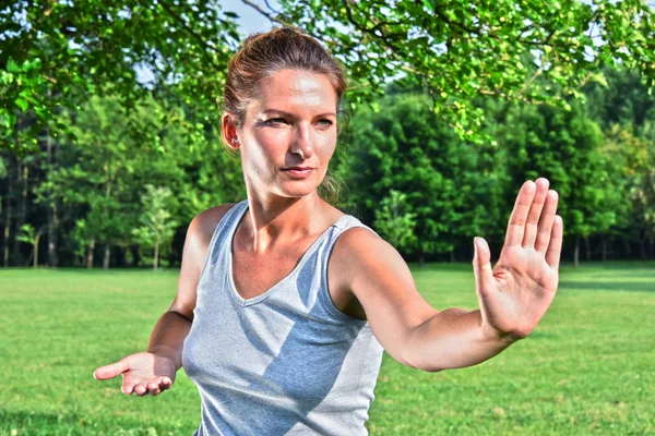 Mujer joven durante el ejercicio de tai chi en el parque —  Fotos de Stock