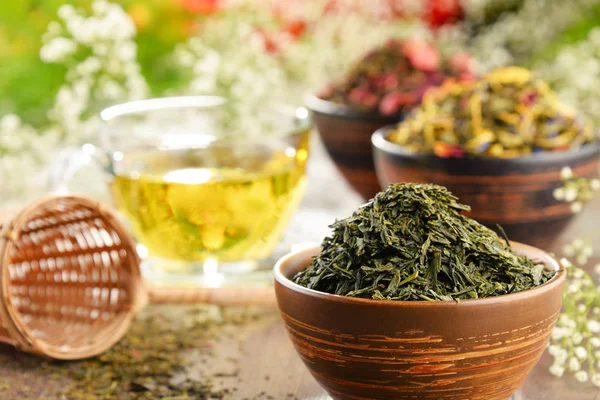 Samenstelling met kop van thee en kommen van thee bladeren — Stockfoto