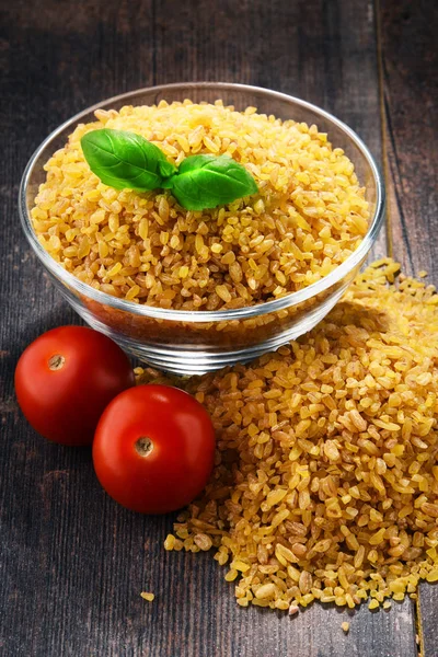 Tigela de bulgur não cozido na mesa de madeira — Fotografia de Stock