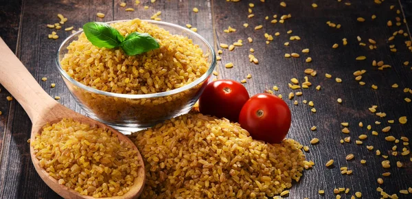 Tigela de bulgur não cozido na mesa de madeira — Fotografia de Stock