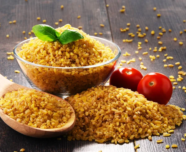 Bowl of uncooked bulgur on wooden table — Stock Photo, Image