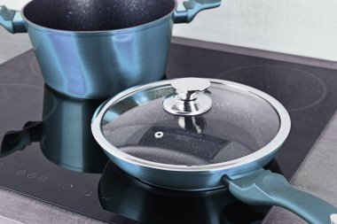Frying pan and steel pot on modern induction cooktop clipart