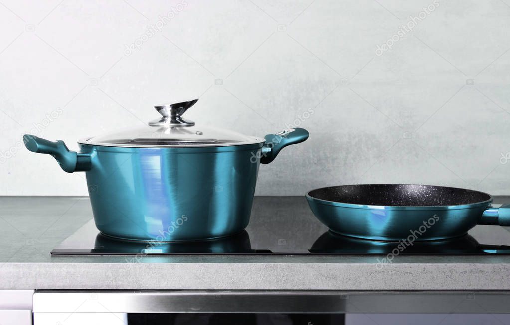 Frying pan and steel pot on modern induction cooktop