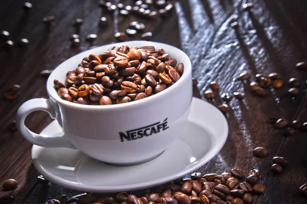 Sammansättning med kopp Nescafe kaffe bönor — Stockfoto