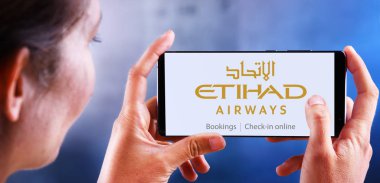 Etihad Havayollarının logosunu gösteren akıllı telefon tutan bir kadın.