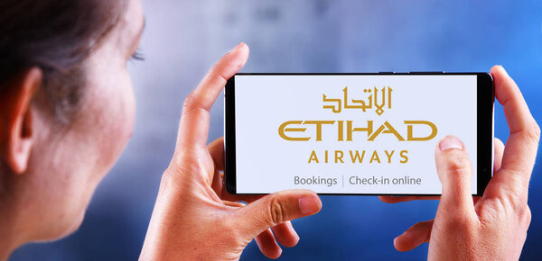 Woman holding smartphone displaying logo of Etihad Airways
