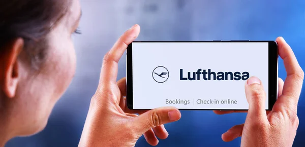 Žena držící smartphone s logem Lufthansa — Stock fotografie