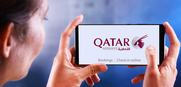 Woman holding smartphone displaying logo of Qatar Airways
