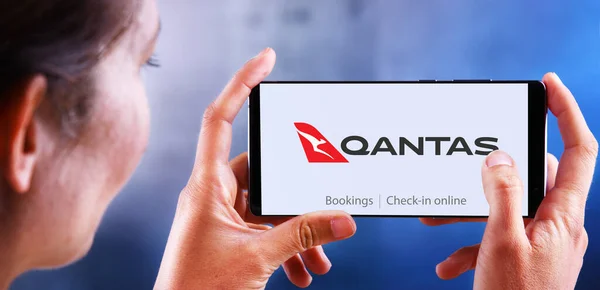 Žena držící smartphone s logem Qantas Airways — Stock fotografie