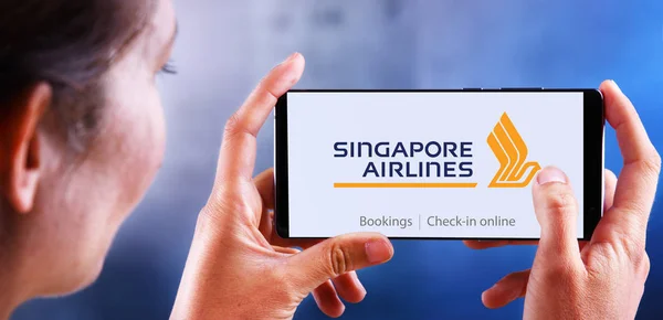 Žena držící smartphone s logem Singapore Airlines — Stock fotografie