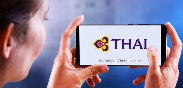 Vrouw met smartphone met logo van Thai Airways — Stockfoto