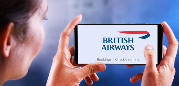 Woman holding smartphone displaying logo of British Airways