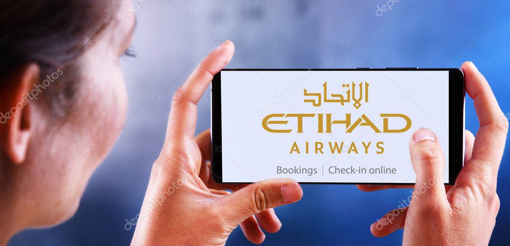 POZNAN, POL - DEC 08, 2019: Woman holding smartphone displaying logo of Etihad Airways headquartered in Khalifa City, Abu Dhabi, UAE