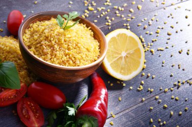 Ahşap masada pişmemiş bir kase bulgur..