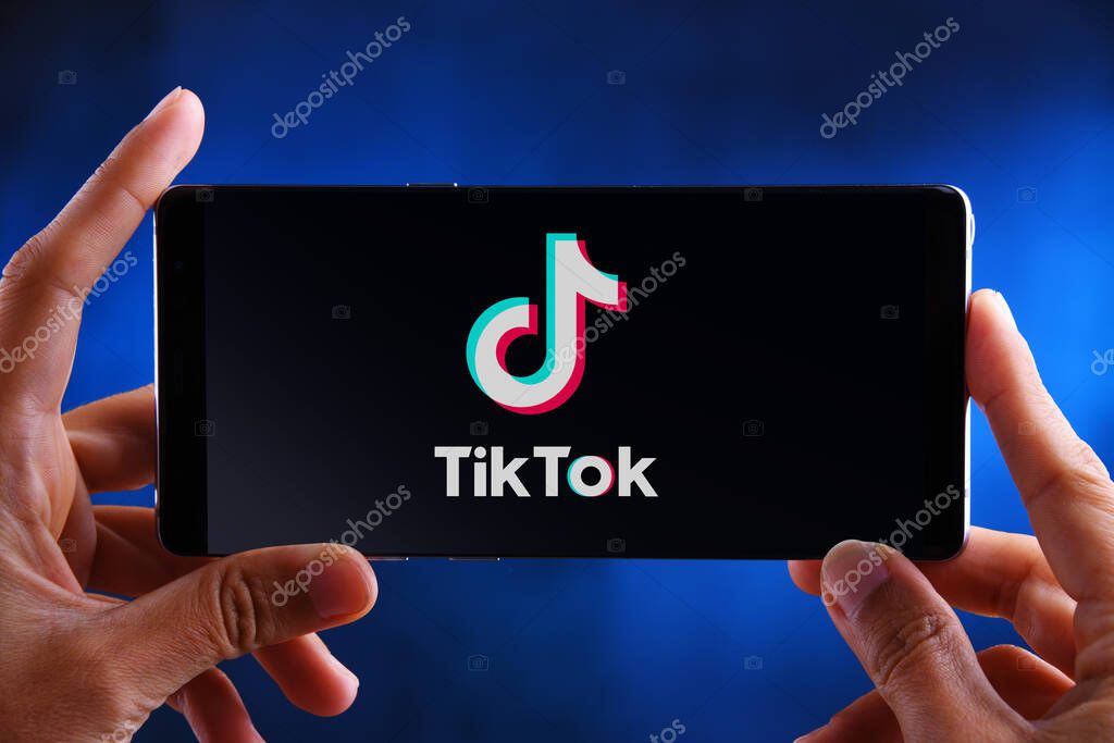 POZNAN, POL - FEB 19, 2020:  Hands holding smartphone displaying logo of TikTok, a Chinese video-sharing social networking service owned by ByteDance