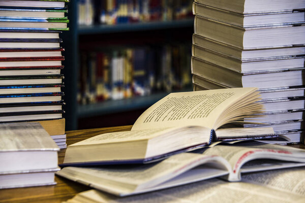 Открытая книга с книгами под и книгами на полках в фоновом режиме
