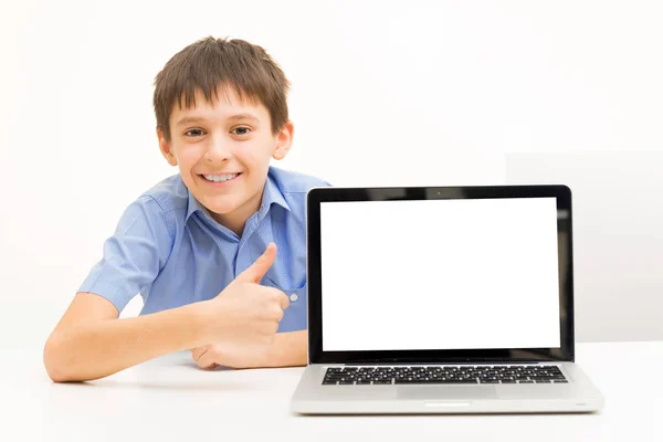 Junge im blauen Hemd benutzt Laptop, der drinnen an einem Tisch sitzt — Stockfoto