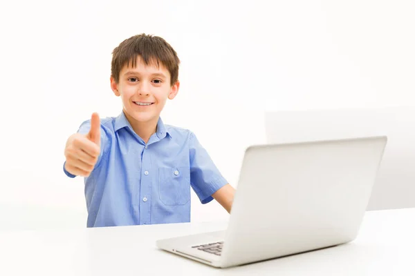 A fiú kék inget használ egy laptop bent ül az asztalnál — Stock Fotó