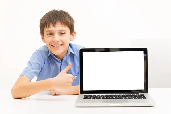 Chłopiec w niebieską koszulę używa laptopa pomieszczeniu siedzi przy stole — Zdjęcie stockowe
