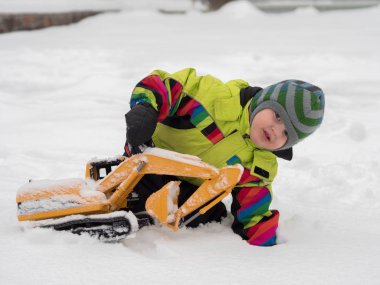 Tarak beyaz karda oynarken kış tulum giymiş şirin çocuk