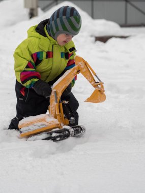 Tarak beyaz karda oynarken kış tulum giymiş şirin çocuk
