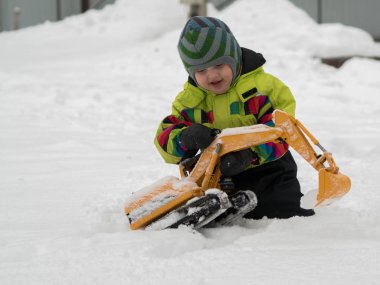 Tarak beyaz karda oynarken kış tulum giymiş şirin çocuk