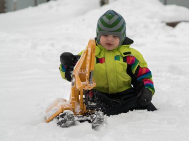 Tarak beyaz karda oynarken kış tulum giymiş şirin çocuk