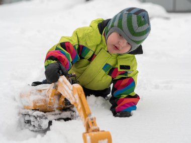 Tarak beyaz karda oynarken kış tulum giymiş şirin çocuk