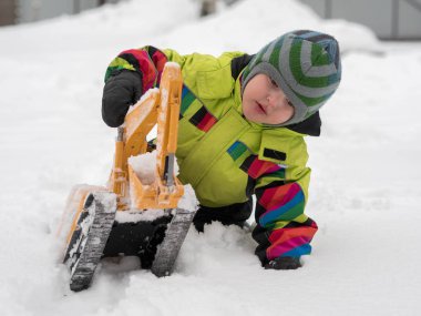 Tarak beyaz karda oynarken kış tulum giymiş şirin çocuk