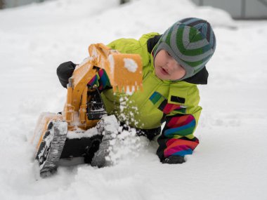 Tarak beyaz karda oynarken kış tulum giymiş şirin çocuk